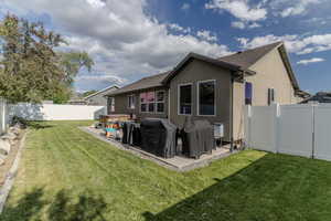 Expansive backyard featuring a manicured lawn, white privacy fencing, and a concrete patio