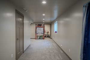Finished basement hallway featuring recessed lighting, light gray carpet, and a window
