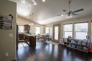 Open-concept living area featuring rich wood-finish flooring and a vaulted ceiling with recessed lighting