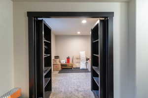 Hidden room featuring a pivoting bookcase door, recessed lighting, and carpeted flooring