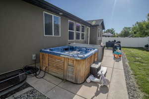 Patio area featuring a built-in spa with wood-finish siding, concrete paving, and a manicured lawn