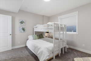 Carpeted room featuring a window with a roller shade, white trim, and a white interior door with a brushed nickel knob