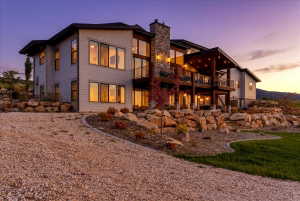 Modern architectural home featuring a multi-level design with a stone chimney and extensive window treatments