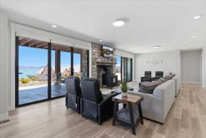 Spacious living area featuring large sliding glass doors, a stone-clad fireplace with a wood-burning stove, recessed lighting, and wood-finish flooring