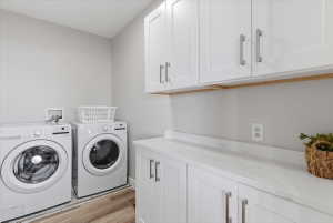 Laundry area featuring white cabinetry with brushed nickel hardware, light-colored countertops, and wood-finish flooring