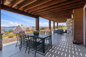 Expansive covered patio featuring a wood-beam ceiling, stone-clad columns, and a concrete floor