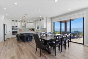 Open-concept living space featuring wood-finish flooring, a kitchen with white cabinetry and an island with bar seating, and a dining area