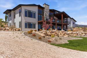 Modern exterior architecture with light-toned siding, dark trim, and a prominent stone chimney