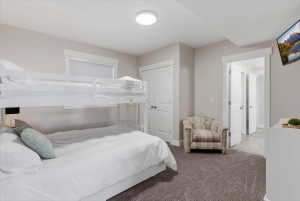 Carpeted bedroom featuring a bunk bed, a mounted television, a built-in closet with bi-fold doors, and a window with blinds