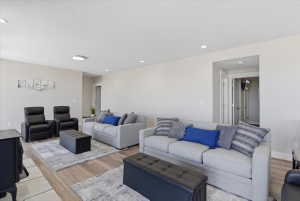 Spacious living area featuring light-toned walls, recessed lighting, and wood-finish flooring