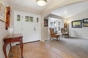 Entryway featuring a white craftsman-style door with sidelights, tile flooring with decorative inlay, and a recessed ceiling light fixture
