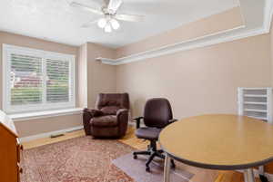 Versatile room featuring a large window with plantation shutters, crown molding, and wood-finish flooring