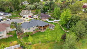Two-story residence with a multi-level deck, dark shingle roof, and light-colored stone exterior