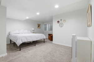 Spacious room featuring neutral carpeting, light-colored walls, recessed lighting, and a window with horizontal blinds