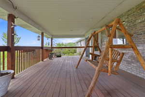 Expansive covered deck featuring wood-finish flooring, a wood railing, and a beadboard ceiling