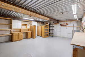Finished lower level featuring a concrete floor, exposed structural beam, and built-in cabinetry