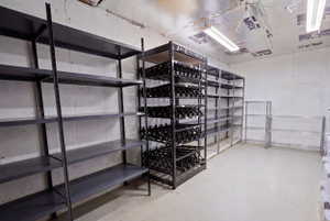 Storage room featuring multiple shelving units, concrete walls, an insulated ceiling, and overhead fluorescent lighting