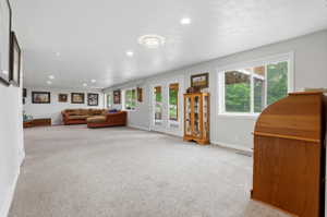 Expansive carpeted room with multiple windows, recessed lighting, and a double glass-paned door