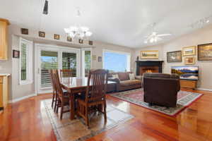 Open-concept living space featuring wood-finish flooring, a fireplace with a dark mantel, and vaulted ceilings