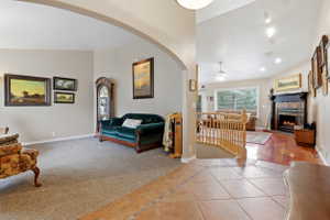 Arched entryway opening to a carpeted living space and a separate area featuring tile flooring