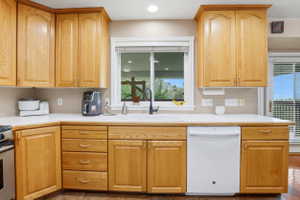 Kitchen featuring light wood cabinetry, a white countertop, and a double basin sink with a black gooseneck faucet