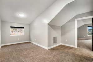 Carpeted room featuring a single window with a roller blind, light gray walls, white baseboards, and a contemporary ceiling light fixture