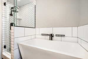 Freestanding soaking tub with a wall-mounted matte black faucet, set against white subway tile wainscoting
