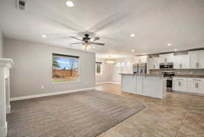 View entering the living area from the entrance. Open-concept living area featuring a fireplace, recessed lighting, and a ceiling fan