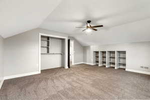 5th Bedroom - Spacious room featuring vaulted ceilings, plush carpet flooring, a ceiling fan with integrated lighting, built-in shelving, and an open closet with shelving and hanging rod