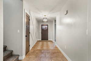 Foyer featuring patterned tile flooring, a dark wood-finish entry door with clear glass panels, and a decorative lantern-style light fixture