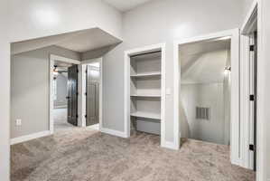 Carpeted landing area featuring built-in shelving, white trim, and a recessed stairway with an integrated light fixture