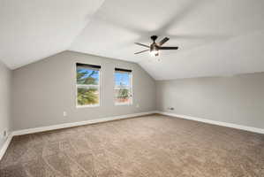 Spacious room featuring vaulted ceilings, neutral-toned walls, and plush carpeting