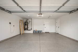 Garage space featuring an epoxy-coated floor, painted walls, two access doors, and overhead lighting