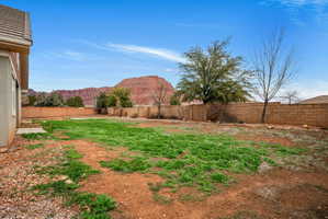 Expansive backyard featuring a partial grass area, surrounded by a block wall fence