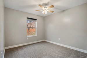 3rd Bedroom - Neutral-toned room featuring a single window, a ceiling fan with integrated lighting, textured carpeting, and white baseboards