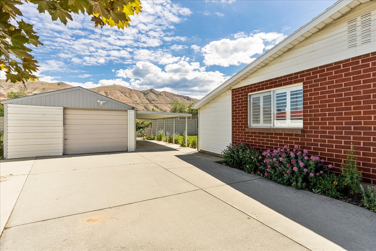 Spacious concrete driveway featuring a detached garage with an attached carport