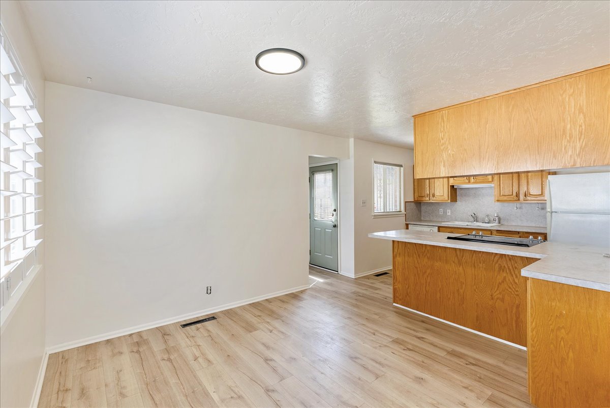Kitchen with a breakfast bar featuring wood-finish cabinetry, a built-in range, and light-toned countertops