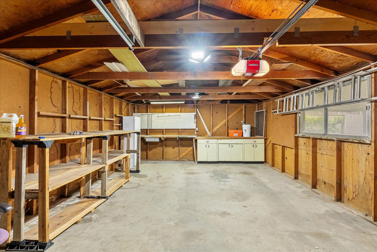 Spacious garage featuring exposed wood beam ceilings and concrete flooring