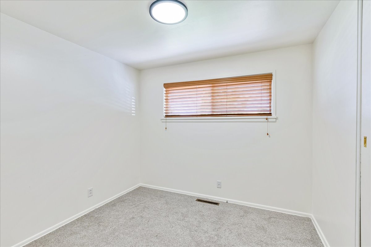 Neutral-toned room featuring a single window with horizontal wood blinds, recessed lighting, light gray carpet, and white walls