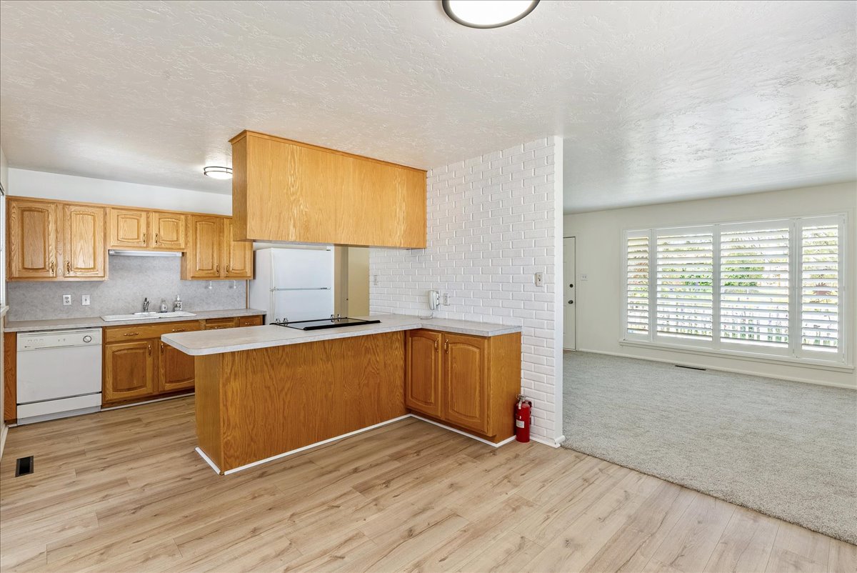 Kitchen featuring wood cabinetry, white appliances, a built-in cooktop, and wood-finish flooring