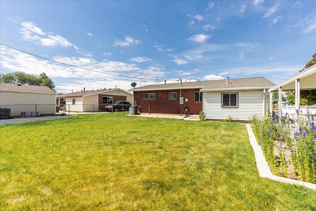 Expansive green lawn with a landscaped planting bed and a brick and siding exterior