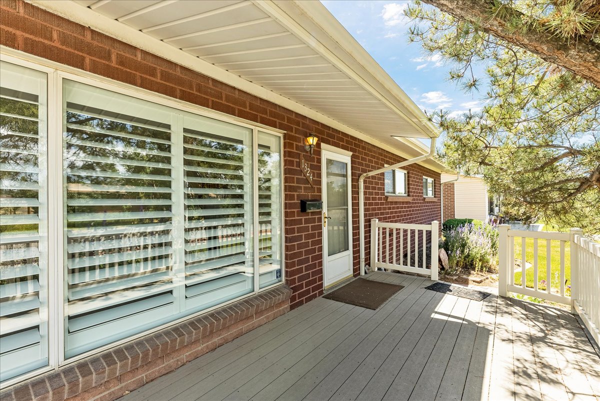 Brick exterior featuring a covered porch with plank decking