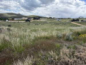 Expansive rural landscape featuring a natural grass field and distant rolling hills