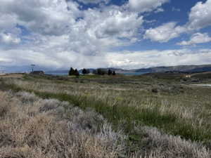 Expansive open land featuring natural grasses and distant water