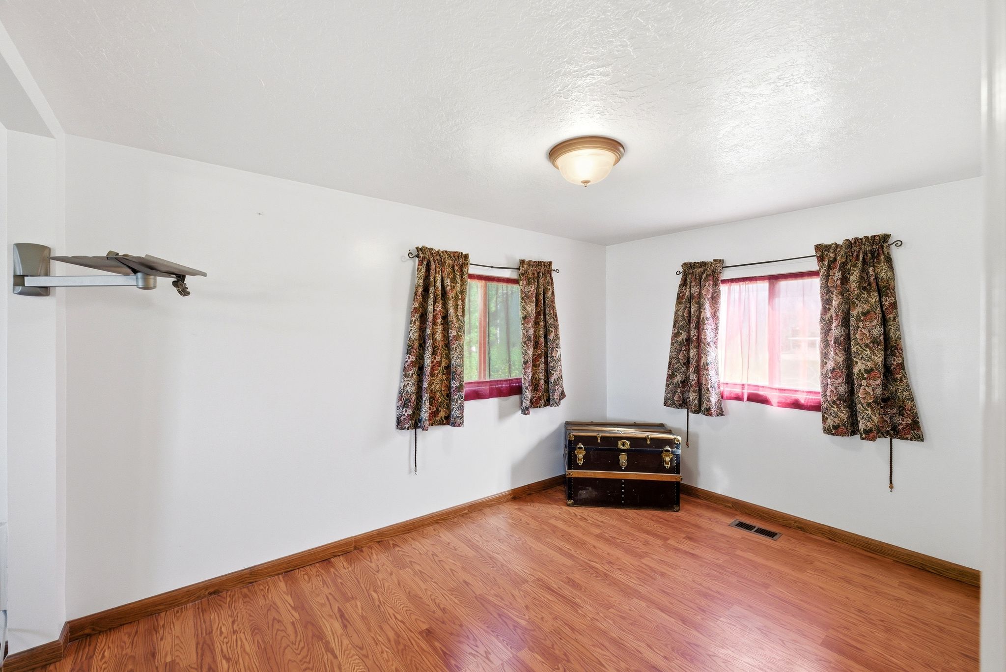 Bright interior space with wood-finish flooring, white walls, and a ceiling-mounted light fixture