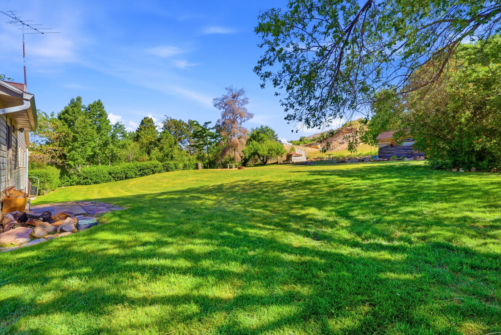 Expansive green lawn with mature trees and a clear blue sky