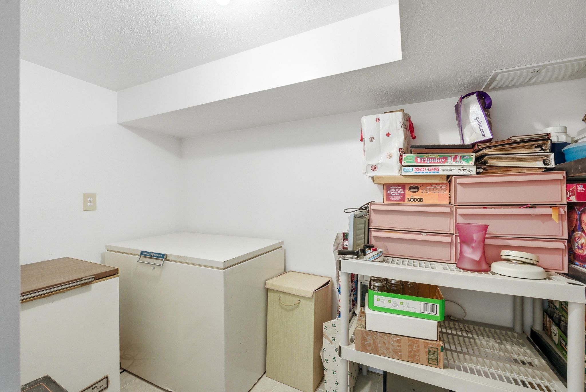 White painted walls with a recessed light fixture, exposed ceiling joist, and electrical outlet