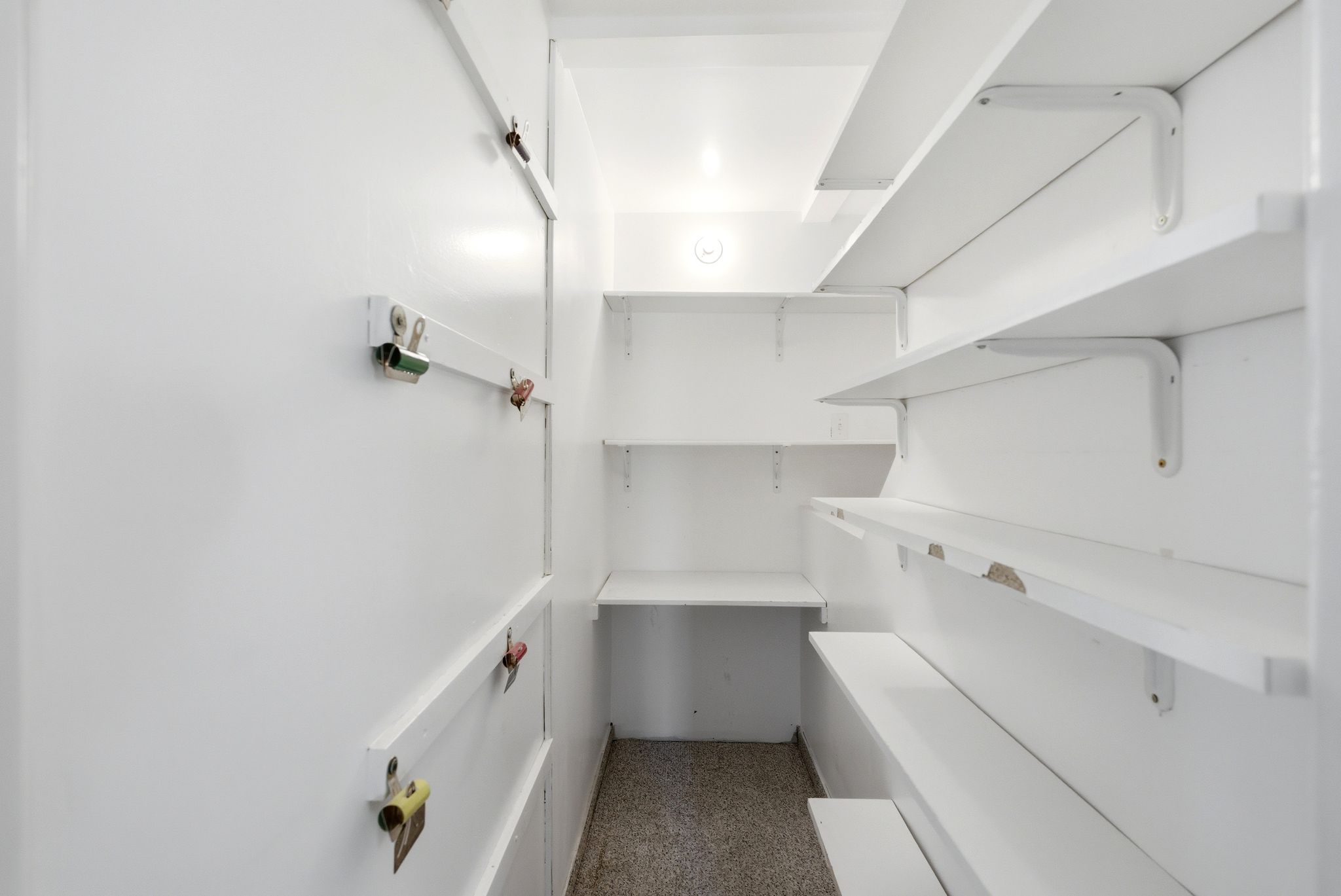 Storage room featuring built-in shelving, white painted walls, and a light-colored floor