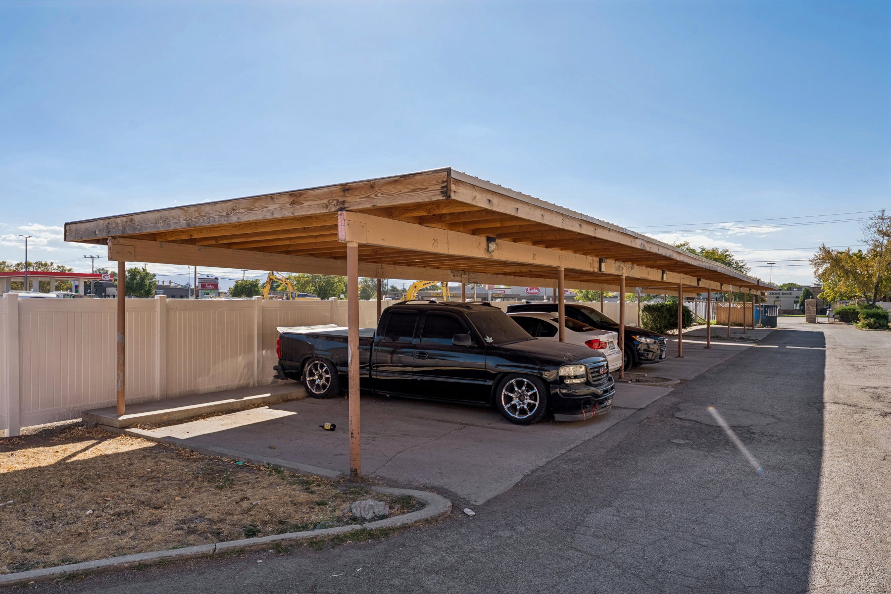 Covered parking area featuring a multi-stall carport with wood framing and a light-colored roof