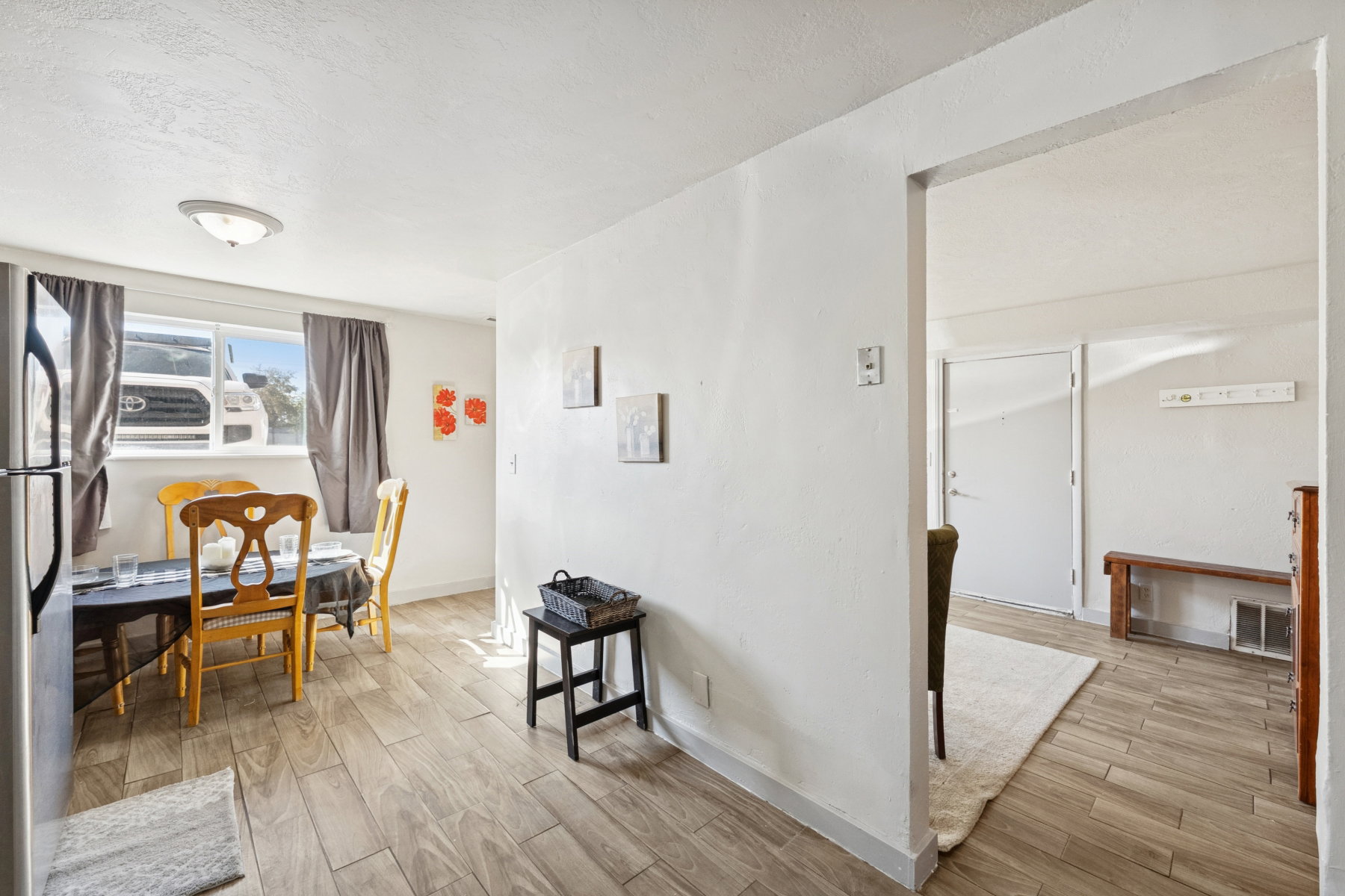 Open-concept living area with wood-finish flooring, white walls, and a window with natural light